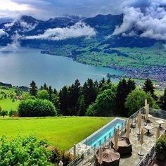 an aerial view of a pool and mountains in the distance with clouds rolling over it