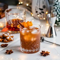 a drink in a glass on a table next to cookies and christmas decorations with lights