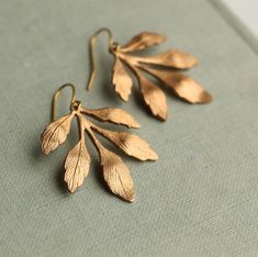 These great chandelier style leaf earrings feature a stylised and beautifully detailed leaf design in a golden brass.  The leaves have subtle texture on the surface to give an interesting, more organic finish.   Each earring measures around 50mm (two inches) in total, and the leaf chandelier is designed to hang below the earlobe.   This piece of handmade jewellery comes packaged in a nice recycled gift box with a tag, all ready to give or keep. 🖤 FASTER SHIPPING 🖤 Need this fast? We offer a Faster Shipping option here: https://www.etsy.com/uk/listing/100107311/faster-shipping-priority-post-upgrade 🖤 GIFT MESSAGE & WRAP SERVICE! 🖤 https://www.etsy.com/uk/listing/750160511/gift-wrap-wrapping-personalised-card?ref=listings_manager_table Gold Leaf Nature-inspired Jewelry, Elegant Brass Leaf Jewelry, Gold Bohemian Leaf-shaped Jewelry, Gold Leaf Nature-inspired Earrings, Nature-inspired Leaf Shaped Brass Jewelry, Cottagecore Earrings, Silk Purse, Gold Leaf Earrings, Chandelier Style