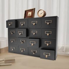 a cabinet with many drawers and a clock on it's side next to a comb dispenser