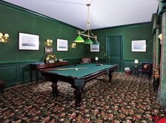 a pool table in the middle of a room with green walls and carpeted floors