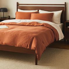 a bed with an orange comforter and two nightstands next to it in a bedroom