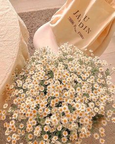 a bouquet of daisies sitting on the floor next to a chair and towel bag