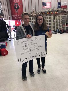 two people standing in a room holding a sign