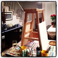 a wooden easel sitting on top of a table covered in paint and art supplies