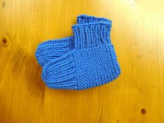 a blue knitted mitten sitting on top of a wooden table