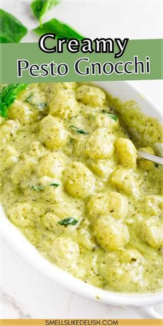 creamy pesto gnocchi in a white bowl with basil leaves on the side