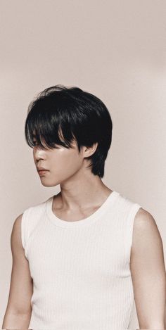 a man with black hair wearing a white tank top