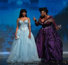 two women in gowns standing next to each other on a stage with blue lights