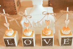 four small boxes with candy on them are decorated with hearts and the word love is spelled in white letters