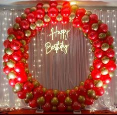 a red and gold balloon arch with happy birthday written on it in the center surrounded by balloons