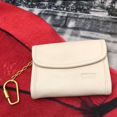 a white purse with a gold chain hanging from it's side on top of a red blanket