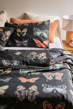 a bed with black and orange butterflies printed on it, along with two nightstands