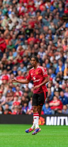 a soccer player is on the field during a game with fans in the stands behind him