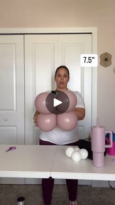 a woman standing in front of a table holding balloons