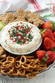 a platter filled with pretzels, crackers, strawberries and cookies