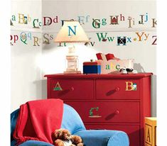 a child's bedroom with blue and red furniture, letters on the wall and teddy bear in chair