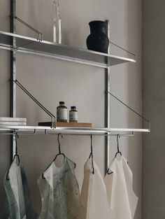 some towels hanging on a metal shelf with bottles and jars next to them in a room