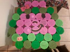 a cardboard box filled with lots of different colored paper circles on top of a tile floor