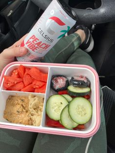 a person holding a tray with food in it and a can of soda on the side