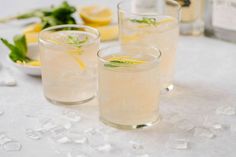 two glasses filled with lemonade sitting on top of a table