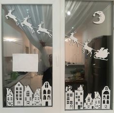 the window is decorated with white paper cutouts and santa's sleigh