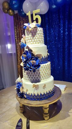 a blue and white wedding cake with balloons in the background