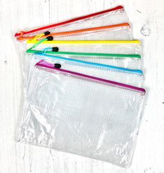 five different colored pencils in a clear bag on a white wooden background with space for text