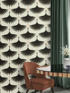 a chair sitting in front of a window next to a wall with black and white designs on it