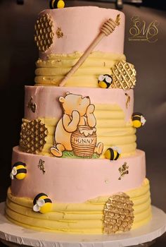 a three tiered cake decorated with honeybees and a winnie the pooh character