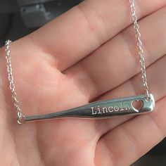 a person holding a necklace with the word lincoln on it and a heart in the middle