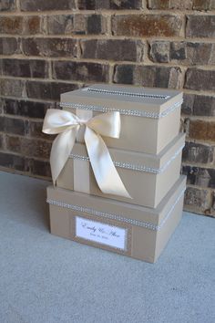 three brown boxes with white bows on them sitting in front of a brick wall and door