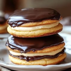 three chocolate covered donuts sitting on top of a white plate next to each other