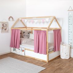 a child's bed with pink curtains and white walls