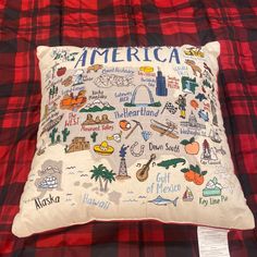 a red and black checkered blanket with a pillow that has an embroidered map of america on it