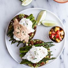 an open face sandwich with asparagus, tomatoes, and other toppings on a white plate