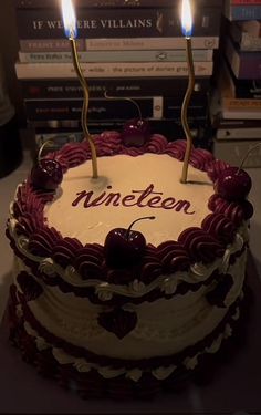 a cake with two candles on top of it and the words nineteen spelled in red