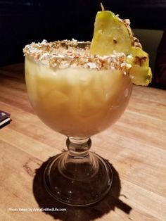 a glass filled with an alcoholic drink sitting on top of a wooden table