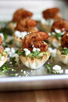 small appetizers with shrimp and feta cheese sit on a silver tray, ready to be eaten