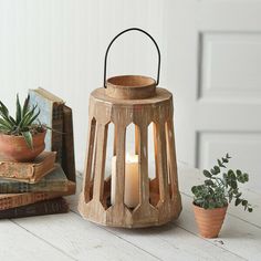 a wooden lantern sitting on top of a table next to books and a potted plant