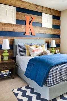 a bedroom decorated in blue and white with wood accenting the walls, along with two lamps on either side of the bed