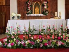 flowers and greenery are arranged in front of the alter