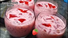 four glasses filled with strawberry milkshakes on top of a table