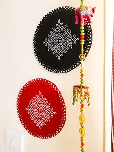 two decorative wall hangings on the side of a white wall next to a red and black plate