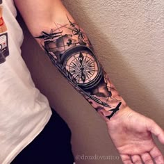 a man with a compass tattoo on his arm