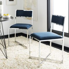 two chairs sitting next to each other on top of a white rug in a room