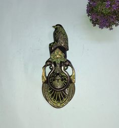 a bird is perched on the handle of a doorknob with purple flowers in the background