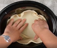 someone is kneading dough into a crock pot with their hands on it