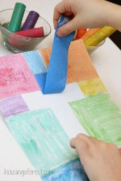 a child's hands painting squares with colored crayons