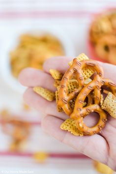 a hand holding up a small cracker and pretzel